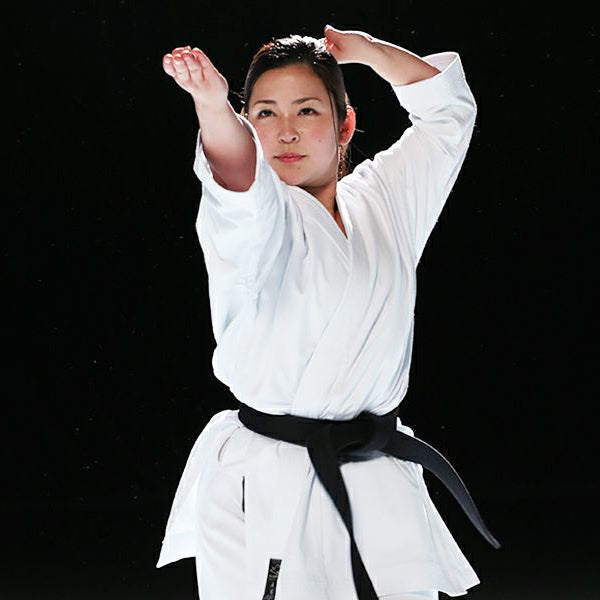Person in a Hayate white martial arts uniform with a black belt against a black background