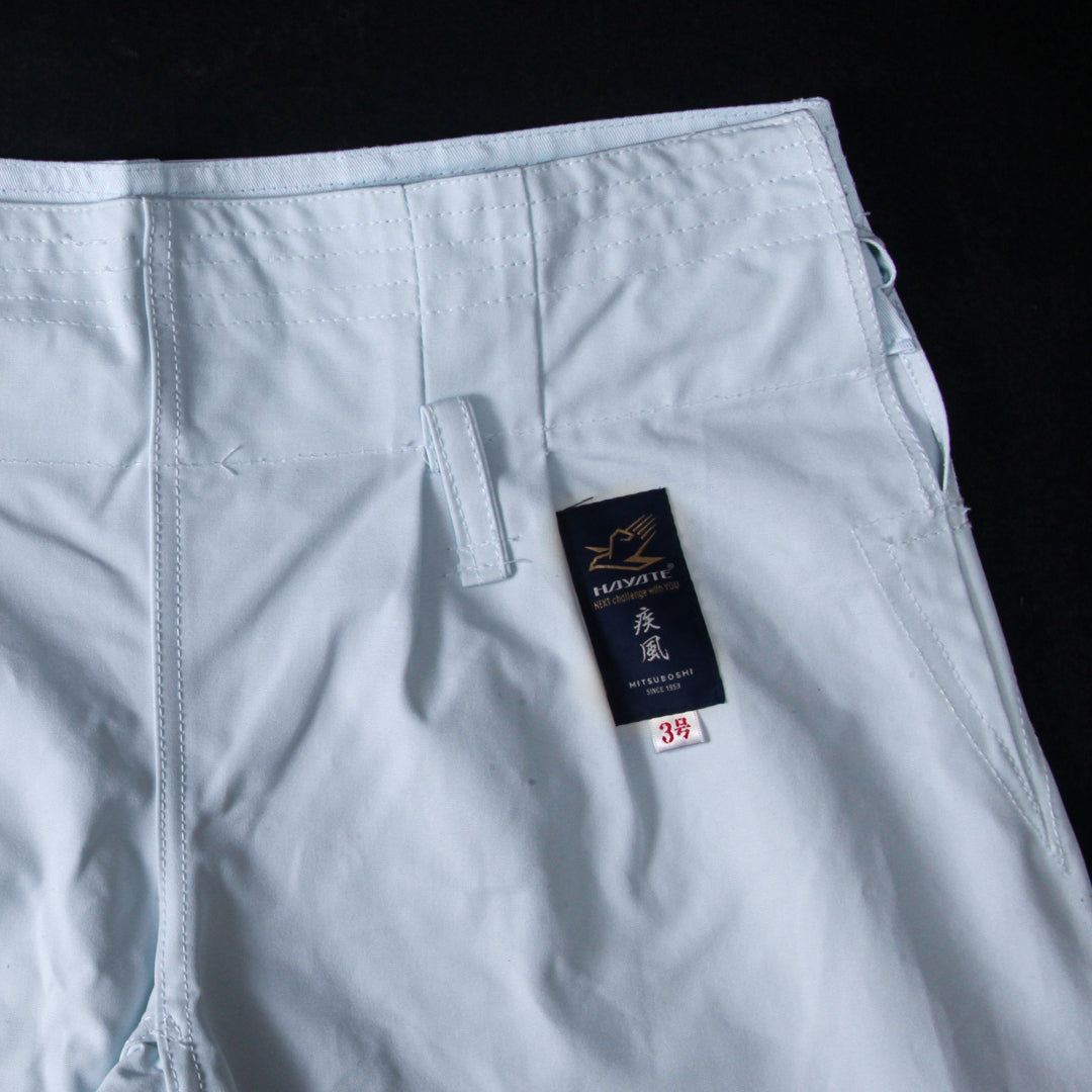 Light blue pants with a brand tag on a black background