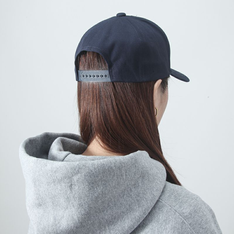 Person wearing a navy cap and gray hoodie from behind on a light gray background